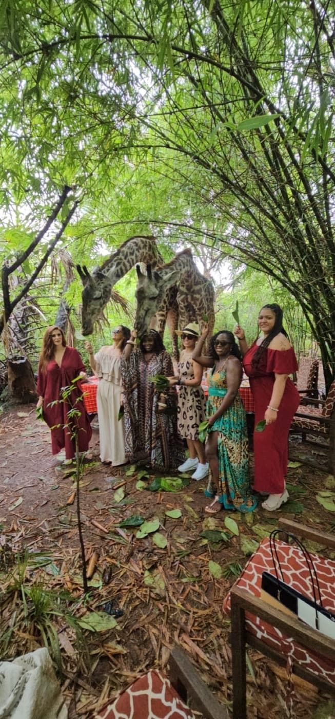 A group of travelers standing beneath giraffes