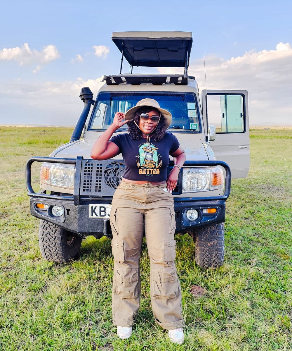 A Diaspora Roots and Routes guest pausing beside a safari vehicle in Kenya